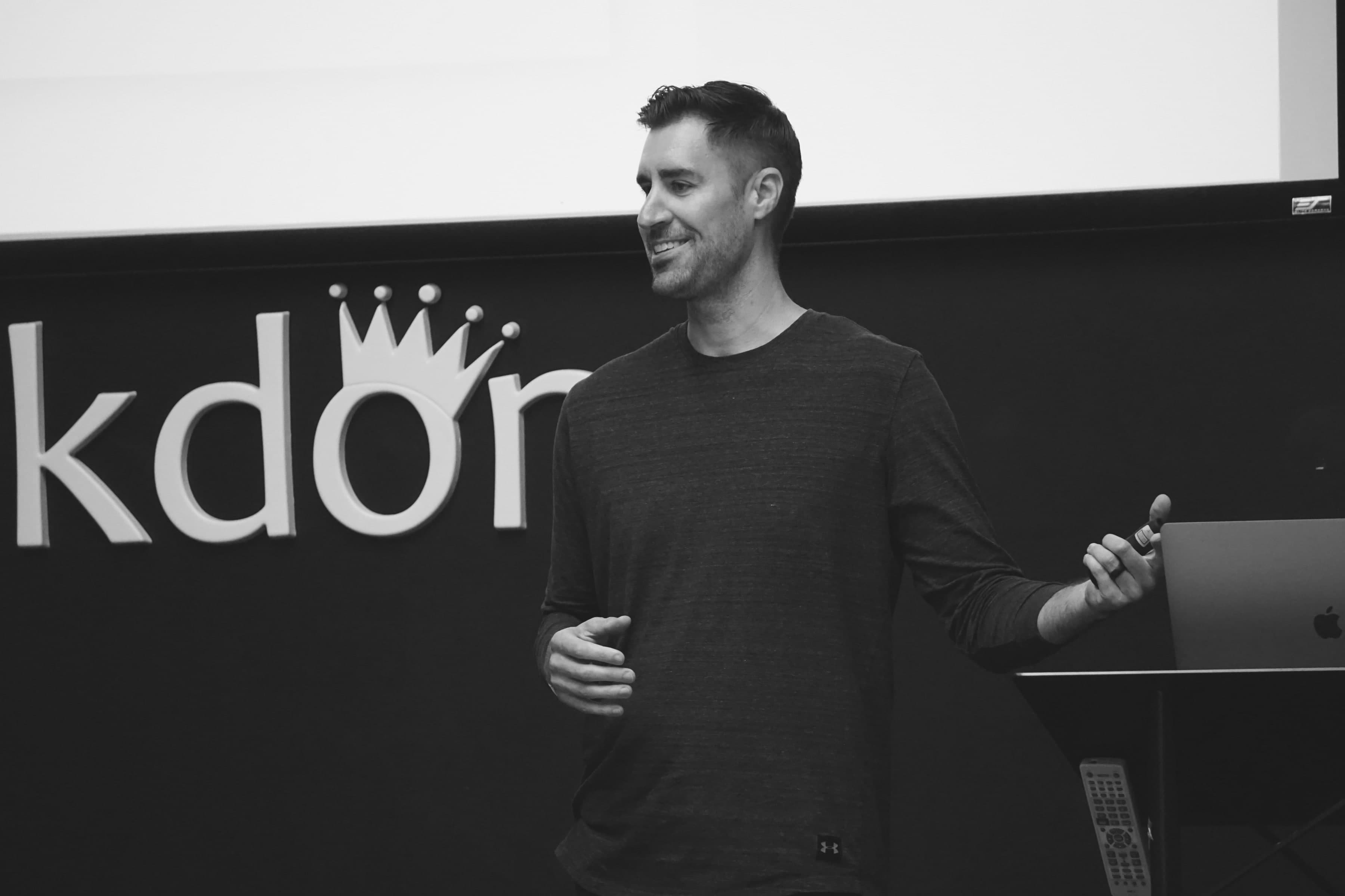 A speaker presenting in front of the Geekdom sign, 2014.