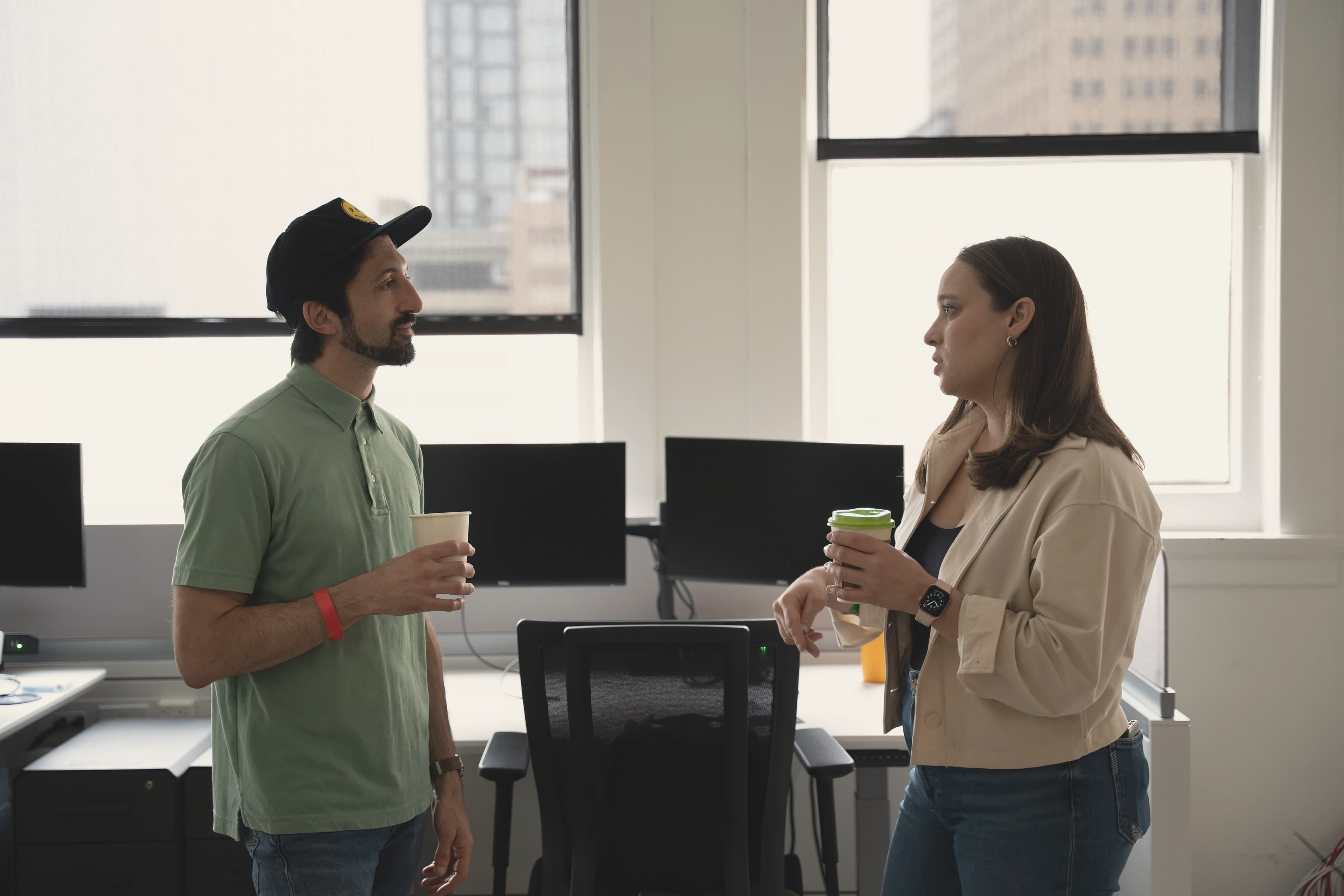 Two members talking over coffee by the third-floor windows, with downtown San Antonio's towers behind them.
