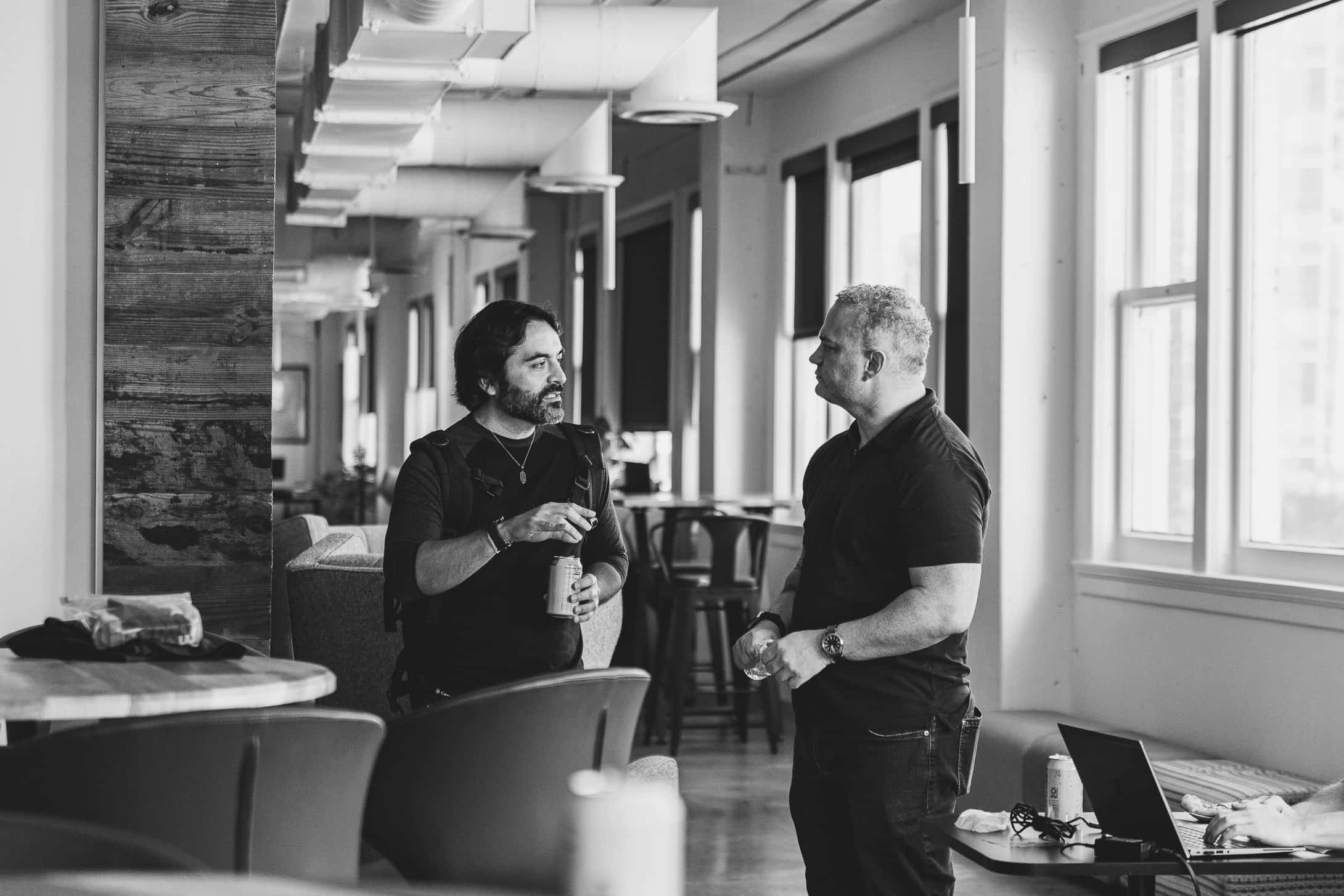 Two people in close conversation in the long room, in black and white.